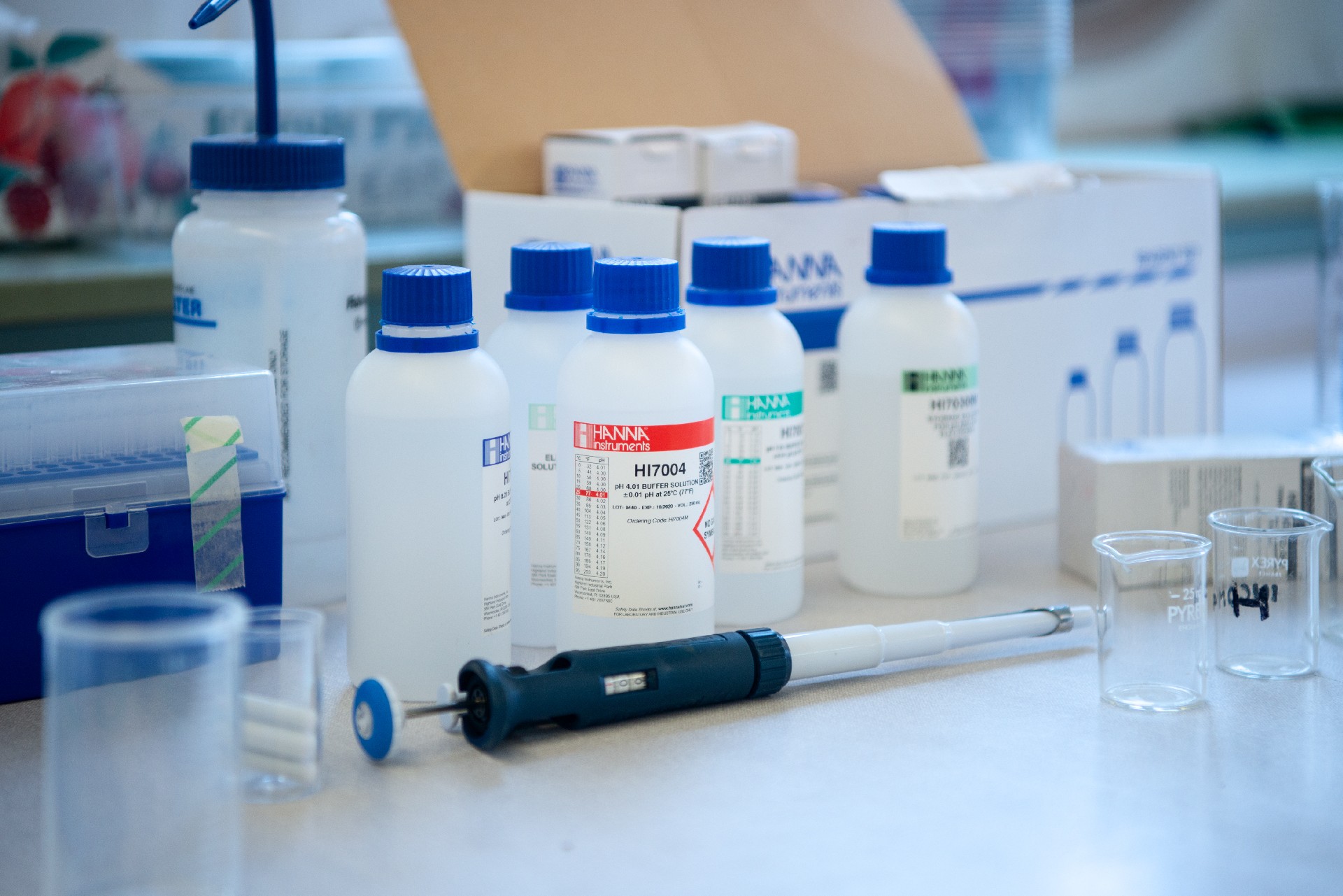Laboratory workbench with bottles of buffer solutions, a pipette, and beakers
